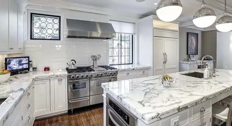 Bright kitchen featuring white cabinetry and elegant white marble countertops with gray veining on the island and counters.